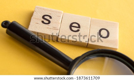 SEO search engine optimization text wooden cubes and magnifying glass on a yellow background. Idea, vision, strategy, analysis, Keyword and content concept.