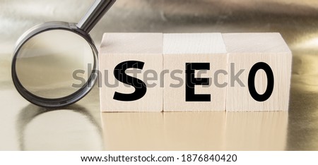SEO search engine optimization text wooden cubes and magnifying glass on a Golden background. Idea, vision, strategy, analysis, Keyword and content concept.
