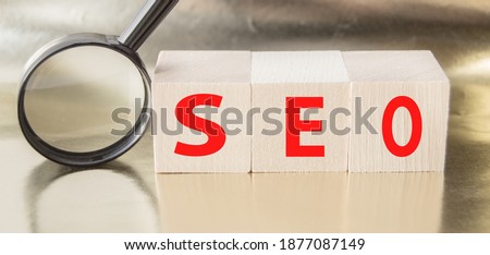 SEO search engine optimization text wooden cubes and magnifying glass on a Golden background. Idea, vision, strategy, analysis, Keyword and content concept.