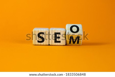 SEO versus SEM. Turned a cube and changed the expression 'SEO' to 'SEM' or vice versa. Concept for Search Engine Optimization and Search Engine Matketing. Beautiful orange background, copy space.