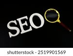 Seo words (Search Engine Optimization) letters with magnifying glass on black background