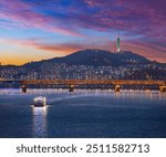 Seoul City after sunset and a sightseeing boat on the Han River and a bridge with Namsan Mountain and Seoul Tower in the background, Seoul, South Korea.