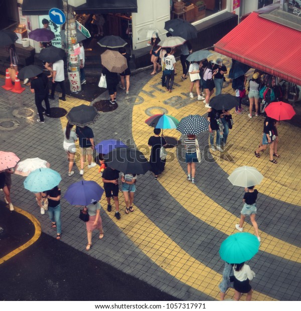 Seoul - July 2017: People with\
umbrellas on a rainy day at Hongdae district. Elevated\
view.