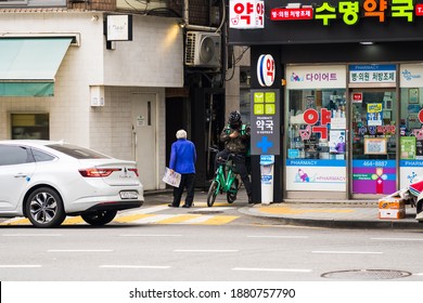 Seoul, South Korea-December 2020: Korean Delivery Driver With Bike At The Alley Way Beside A Pharmacy In Seoul, South Korea