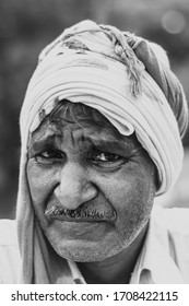 Sep 05, 2019/ Chhattarpur, New Delhi: India- Black And White Portrait Of A Poor 55-60 Years Old Indian Farmer Wearing A Headscarf Looking At The Camera And Sweating In Afternoon.