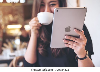 Sep 23th 2017 : A Beautiful Asian Woman With Smiley Face Holding And Using Ipad Tablet Pc While Drinking Coffee In Modern Cafe, Chiang Mai Thailand