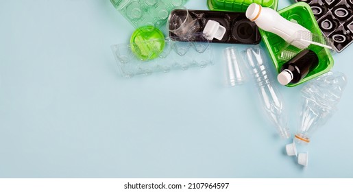 Separate collection of plastic garbage. PET stuff for recycle on blue background. Eco friendly concept. Recyclable plastic waste: aggs, candy box, bottle, meat container. Kind of polyethylene plastic 