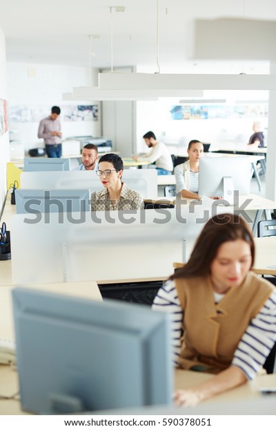 Separate workplace cubicles with\
different people sitting at them in open space of modern\
office
