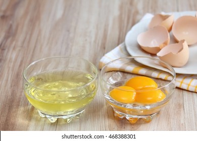 Separated egg white and yolks into two bowls and broken egg shells  are at background 