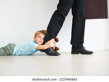 Separation Anxiety In Action. Portrait Of A Cute Young Boy Holding Onto His Dads Leg As He Tries To Leave For Work.