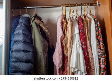 Separation Of The Wardrobe For Summer And Winter. Clothes On Hangers In Dark And Light Colors