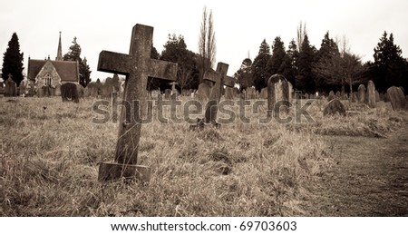 Sepia image of an old cemetary in Suffolk, UK; focus on near gravestone with shallow depth of field