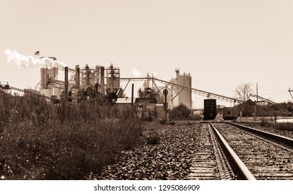 Sepia Mining Operation Pollution And Climate Change. Factory In Texas Producing Fossil Fuel Smoke Stack And Train Tracks Leading To Industrial Revolution Style Like