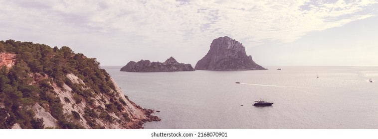 Sepia shot of steep slope of cape Cap Blanc, rocky islands Es Vedra and its satellite Es Vedranell, several boats and yachts on ripples. Mediterranean sea, Ibiza, Balearic Islands, Spain - Shutterstock ID 2168070901