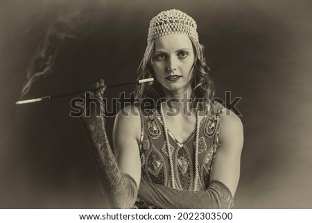 Sepia toned 1920's style vintage photo of a woman in a flapper dress smoking a long filter cigarette.
