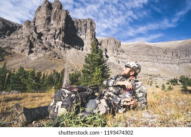 SEPTEMBER 16 2018 - DUBOIS, WYOMING: Elk Hunter Taking A Break, Eating Trail Mix In A Bag, With View Of The Wind River Range Of The Rocky Mountains In The Background. Wearing Camouflage In The Fall