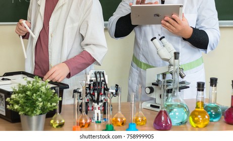 September, 2017 - Belarus, Minsk. Women Teacher And Teenager Student Are In Chemistry Class. Tey Make Test. STEM Education. Lego Mindstorm Robot, Mechanic, Chemistry, Biology. They Use Apple Ipad.