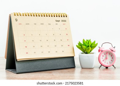 September 2022 green Desk calendar with pink alarm clock on wooden table. - Shutterstock ID 2175023581