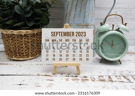 September 2023 monthly calendar with green leaf decoration on wooden background