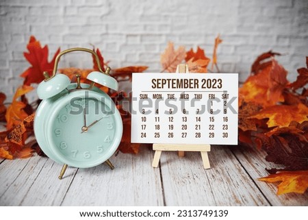 September 2023 monthly calendar maple leaf decoration on wooden background
