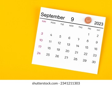 September 2023 and wooden push pin on yellow background.