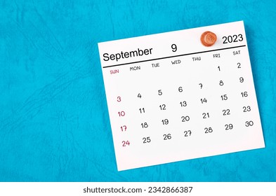 September 2023 and wooden push pin on blue background.