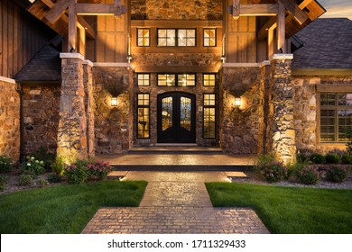 SEPTEMBER 5, 2019 - CHICAGO, IL, USA: A luxury home with a fancy iron door, surrounded by windows and a rock exterior. Warm bulbs light the outside and inside of the property at sunset.