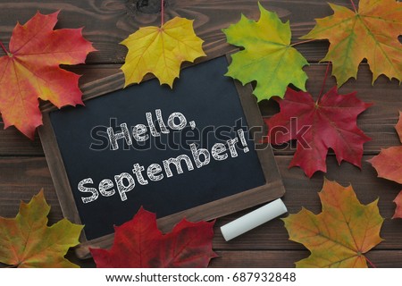 September, back to school concept. Hello September words on chalkboard. Dark brown wooden background. Top view.