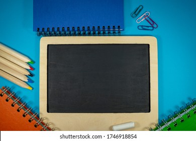 September Still Life With Chalks And Chalk Board, Spiral Ring Bound Notebooks, Pencils And Scattered Paper Clips. Flat Lay, View From Above