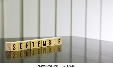 SEPTEMBER Word On Wooden Cube On Black Gloss Wooden Table. Selected Focus