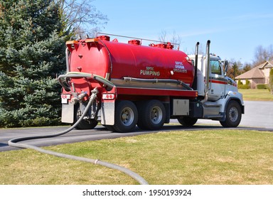 A Septic Pumping Tanker Truck With A Long Hose Going To The Backyard Tank.