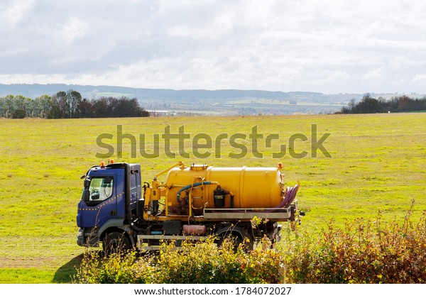 Septic truck on field with grass. Sewage Tank\
truck. Sewer pumping\
machine.