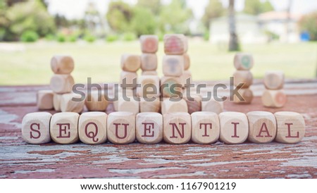 Sequential word written on cube shape wooden blocks on wooden table.