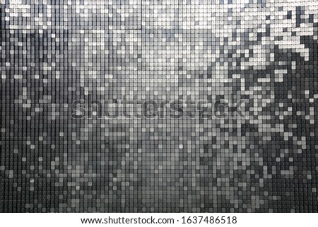 Sequin background. Silver square sequins shimmering in the sun. Reflecting colors of the rainbow including blue, gray, silver, green, black, red, yellow and more. Backgrounds and Textures. Photo Booth