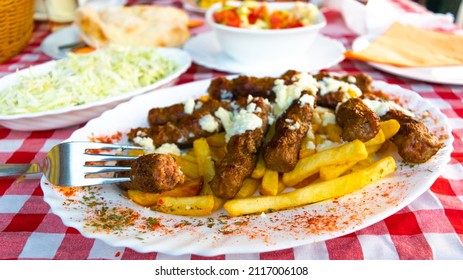 Serbian national dish cevapcici or cevapi (minced meat sausages reminiscent of kebab) along with french fries and salads in the background. The concept of national food.