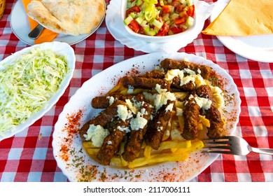 Serbian national dish cevapcici or cevapi (minced meat sausages reminiscent of kebab) along with french fries and salads in the background. The concept of national food.