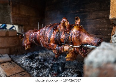 Serbian "Pecenje" pig on a skewer turning over hot ash for an Orthodox event called "slava"