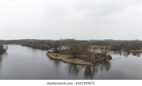Serene aerial view of a calm river meandering through a lush forest landscape with overcast skies, showcasing the tranquil beauty of nature. - Powered by Shutterstock