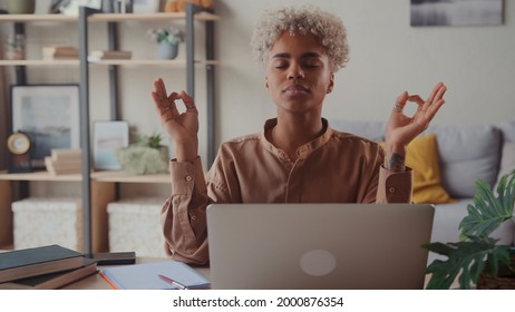 Serene Afro American Woman Relieving Fatigue At Workplace Make Meditation Practice Closed Her Eyes Makes Breathing Exercise Seated At Desk With Laptop. No Anxiety And Stress During Workday In Office