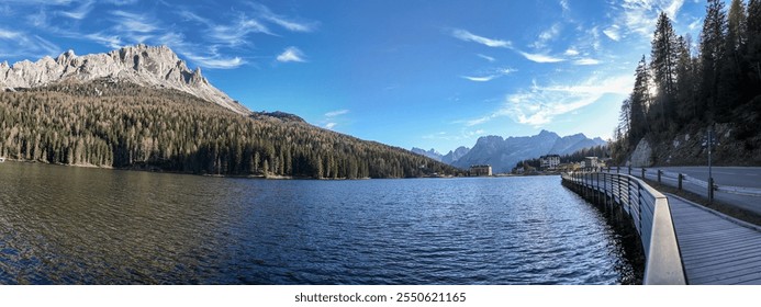 A serene alpine lake with a wooden walkway, surrounded by mountains and forests, ideal for nature holidays and relaxation Dolomite Alps - Powered by Shutterstock