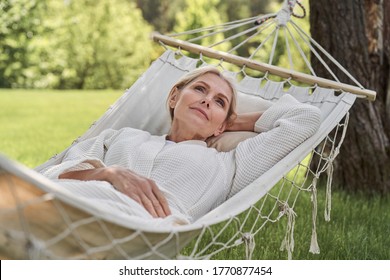 Serene attractive woman is spending weekend in nature and having rest in open air on sunny day