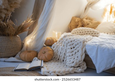 A serene autumn atmosphere features pumpkin near bed with a cozy knitted blanket, enhancing the inviting feel of a relaxed reading nook. - Powered by Shutterstock