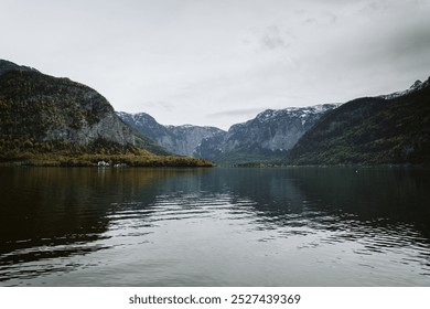 A serene autumn day in Hallstatt, Austria, where vibrant foliage frames the charming lakeside village, reflecting perfectly on the still waters of Lake Hallstatt. - Powered by Shutterstock