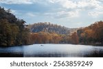 Serene Autumn Lake in Broken Bow, Oklahoma, with a Lone Boat and Vibrant Trees