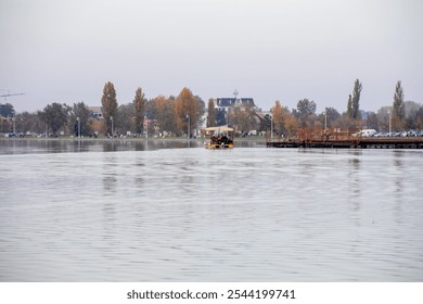 A serene autumn lake scene with a small ferry near a pier, capturing the essence of peaceful travel and leisure - Powered by Shutterstock