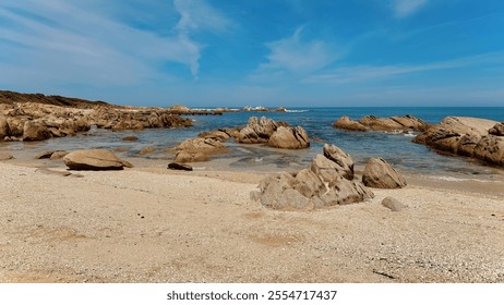 A serene beach scene featuring rocky shores, clear blue waters, and a vast sky, inviting relaxation and exploration. - Powered by Shutterstock