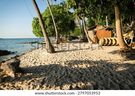 A serene beach scene featuring a rustic wooden hut nestled among lush palm trees. The sandy shore leads to calm, clear waters, perfect for vacation or travel advertising. Golden-hour lighting enhances the warm, inviting atmosphere, ideal for promoting relaxation, tourism, or coastal lifestyle content. The hut’s simple design and natural surroundings create a peaceful escape, emphasizing untouched beauty and tranquility. Great for travel brochures, resort marketing, or nature-inspired campaigns.