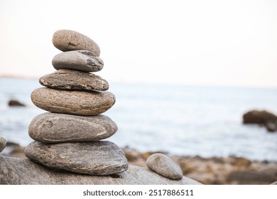 serene beach scene with smooth rocks stacked in a balanced formation. The tranquil atmosphere evokes a sense of zen, harmony, and peace, symbolizing balance and mindfulness in nature - Powered by Shutterstock