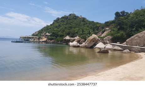 Serene beach view with clear waters and rocky coastline at a tropical paradise during midday - Powered by Shutterstock