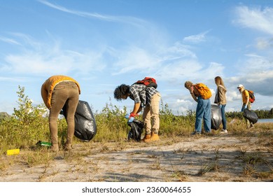 In the serene beauty of nature, a diverse group of friends spanning different ages comes together with a common purpose. They gather along the peaceful shore of a forest lake, armed with rubber gloves - Powered by Shutterstock